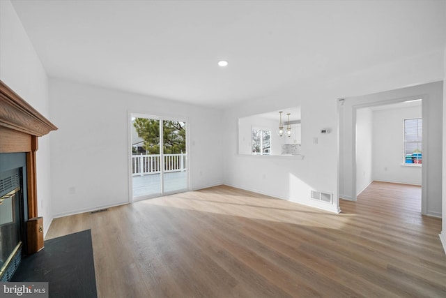 unfurnished living room featuring an inviting chandelier and wood-type flooring