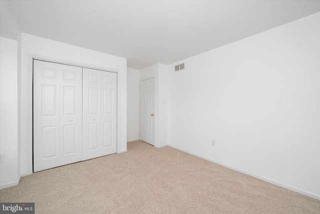 unfurnished bedroom featuring light colored carpet and a closet