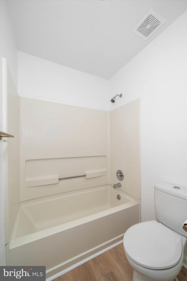 bathroom with shower / tub combination, wood-type flooring, and toilet