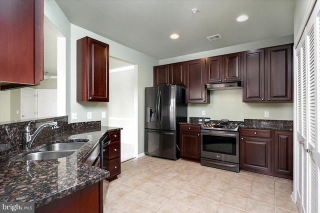 kitchen with light tile patterned flooring, appliances with stainless steel finishes, sink, and dark stone counters