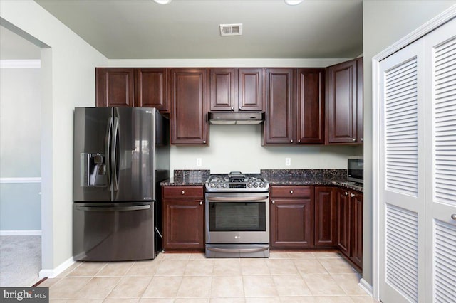 kitchen with light tile patterned floors, dark stone counters, and appliances with stainless steel finishes