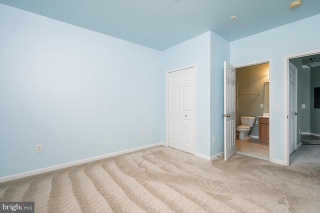 unfurnished bedroom featuring light carpet, connected bathroom, and a closet