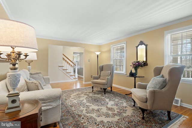 sitting room with light wood-style flooring, visible vents, baseboards, stairway, and crown molding