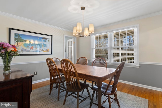 dining space featuring a notable chandelier, crown molding, baseboards, and wood finished floors