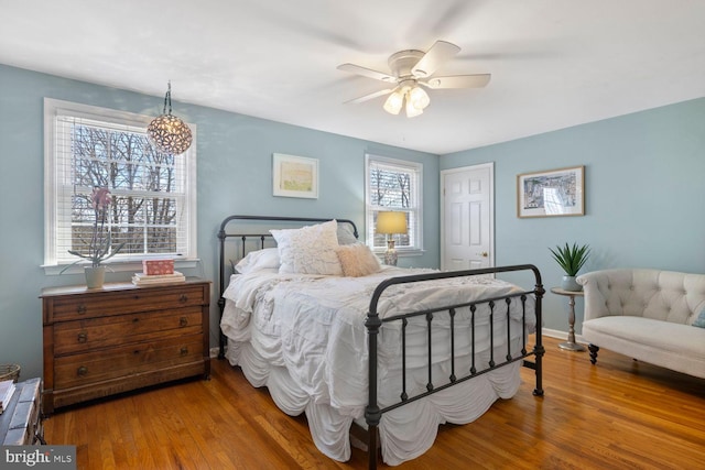 bedroom featuring ceiling fan, baseboards, and wood finished floors