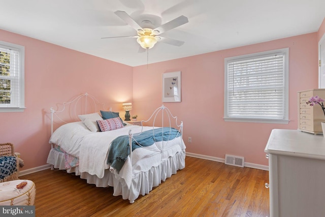 bedroom with baseboards, ceiling fan, visible vents, and light wood-style floors