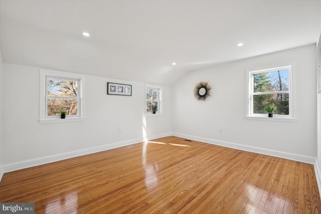 unfurnished room with lofted ceiling, recessed lighting, baseboards, and light wood-type flooring