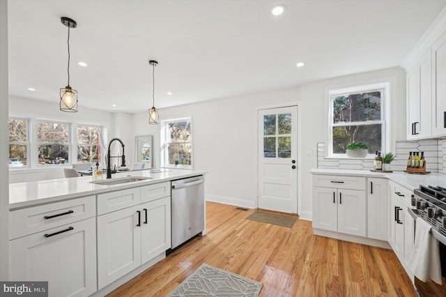 kitchen with light wood-style flooring, a sink, tasteful backsplash, stainless steel appliances, and light countertops