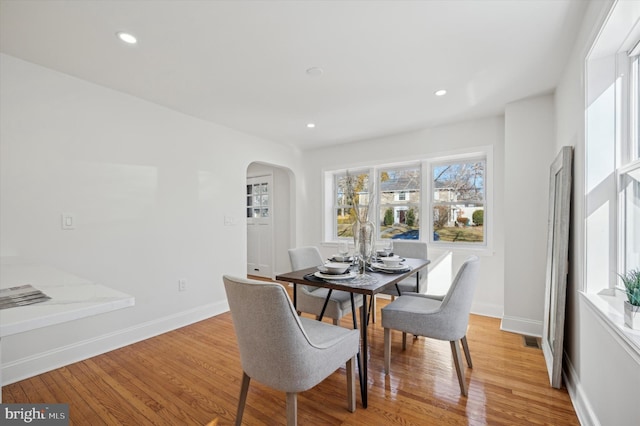 dining space with recessed lighting, baseboards, arched walkways, and light wood-style floors