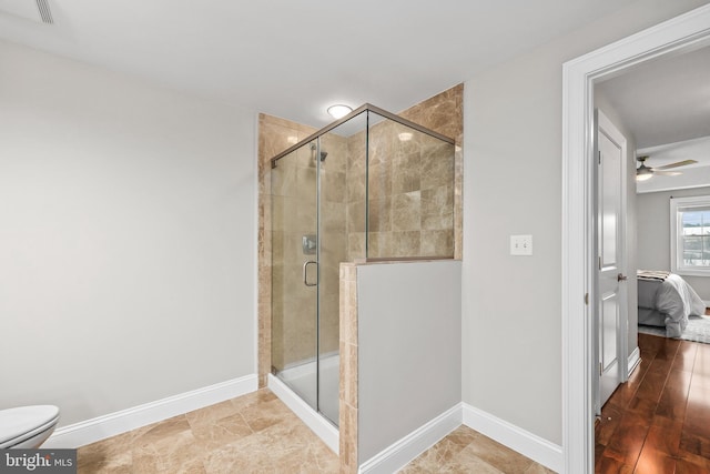 bathroom with ceiling fan, toilet, and a shower with door