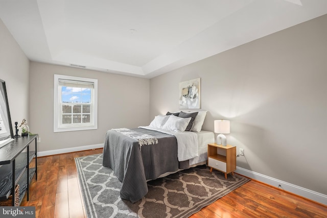 bedroom featuring a tray ceiling and dark hardwood / wood-style floors