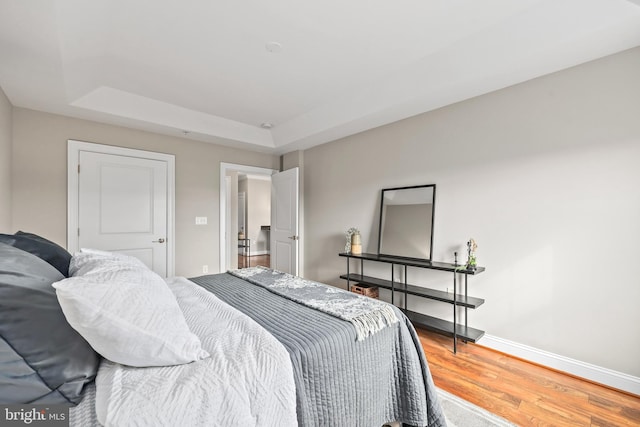 bedroom with hardwood / wood-style flooring and a raised ceiling