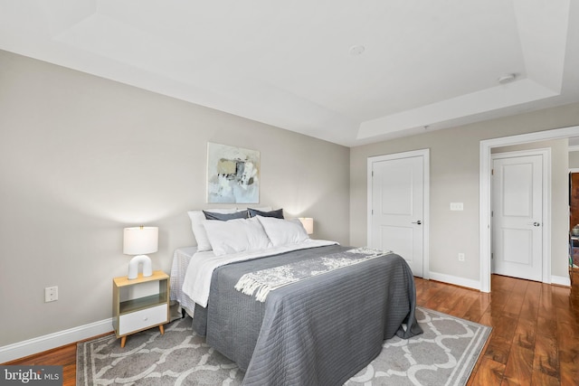 bedroom with a tray ceiling and dark hardwood / wood-style flooring