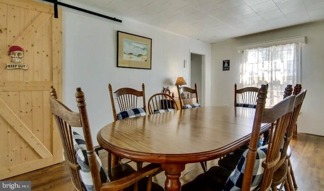 dining room with wood-type flooring and a barn door