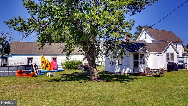 back of property with a yard and a swimming pool