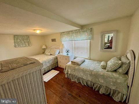 bedroom with beamed ceiling and dark hardwood / wood-style flooring