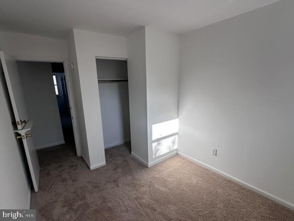 unfurnished bedroom featuring fridge, carpet floors, and a closet