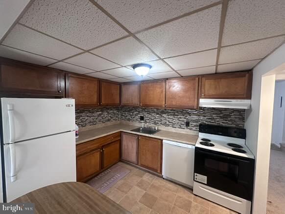 kitchen with tasteful backsplash, sink, a drop ceiling, and white appliances