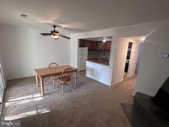 carpeted dining area with ceiling fan