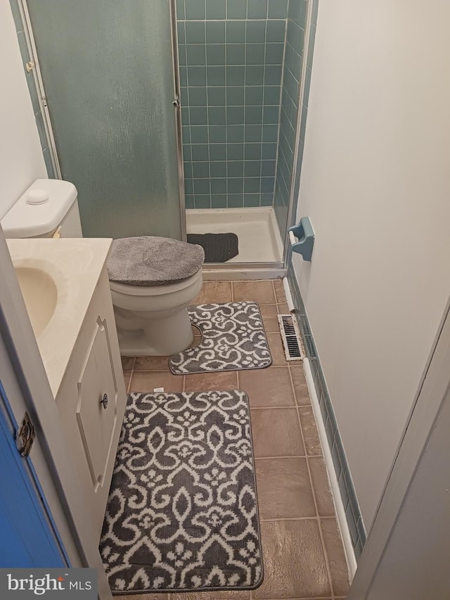 bathroom with an enclosed shower, vanity, tile patterned floors, and toilet