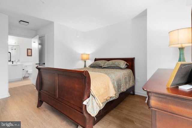 bedroom with connected bathroom and light wood-type flooring