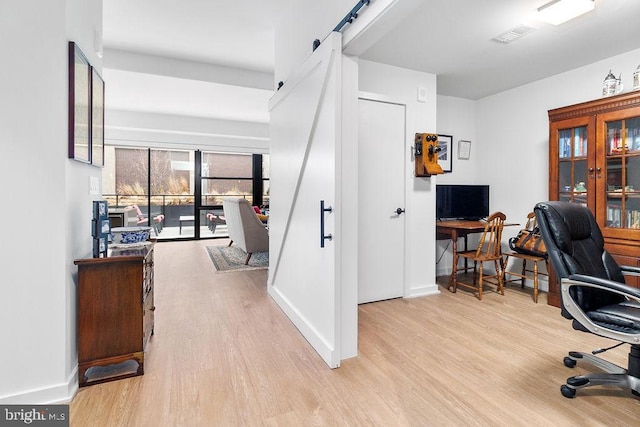 office with light hardwood / wood-style flooring and a barn door