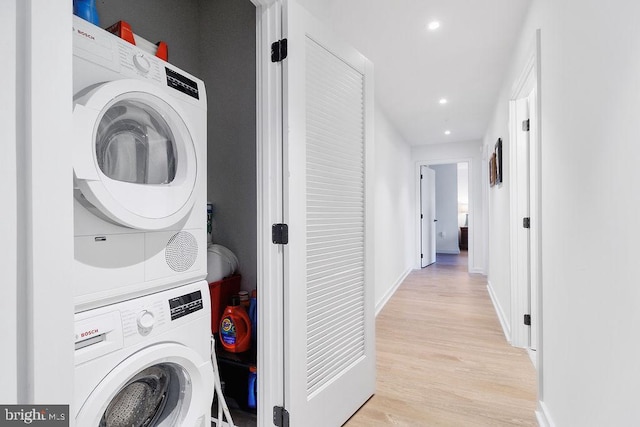 laundry room featuring stacked washer and dryer and light hardwood / wood-style floors