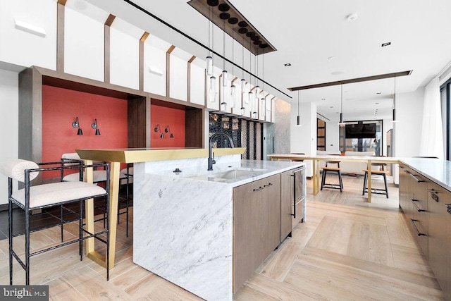 kitchen featuring light parquet floors, sink, pendant lighting, and a large island