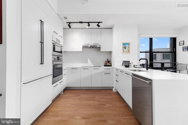 kitchen featuring sink, stainless steel appliances, kitchen peninsula, and white cabinets