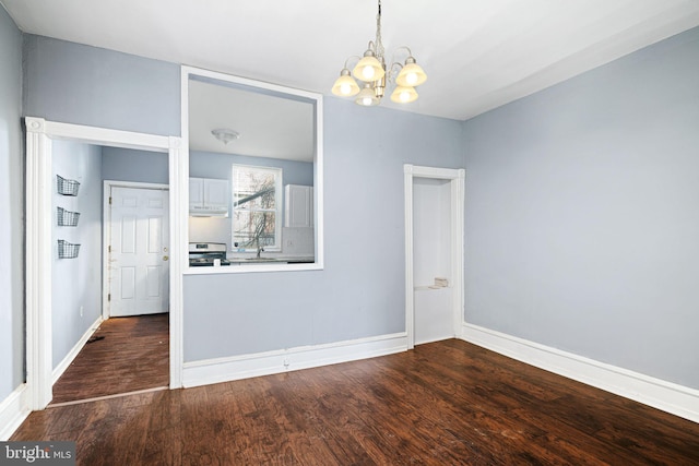 spare room with dark hardwood / wood-style floors and a notable chandelier