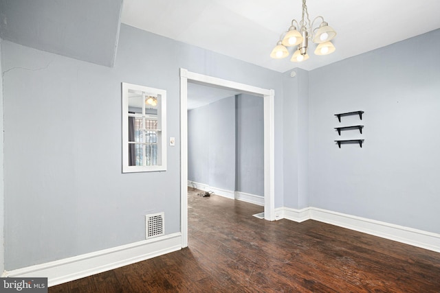 empty room featuring hardwood / wood-style flooring and a chandelier