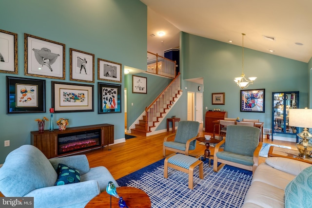 living room featuring hardwood / wood-style flooring, high vaulted ceiling, and an inviting chandelier