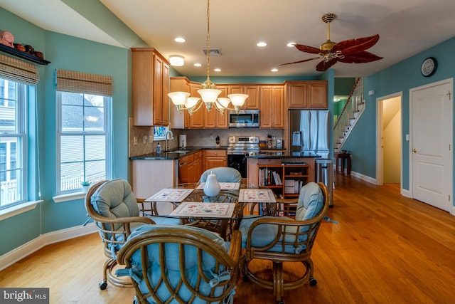 kitchen with sink, appliances with stainless steel finishes, hanging light fixtures, tasteful backsplash, and light wood-type flooring