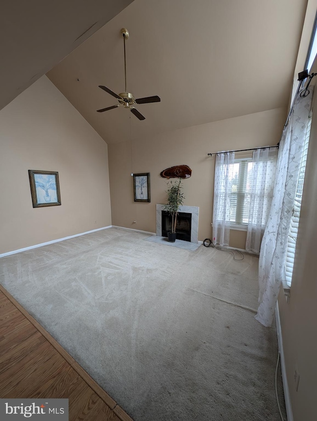 unfurnished living room featuring ceiling fan, carpet floors, a premium fireplace, and high vaulted ceiling