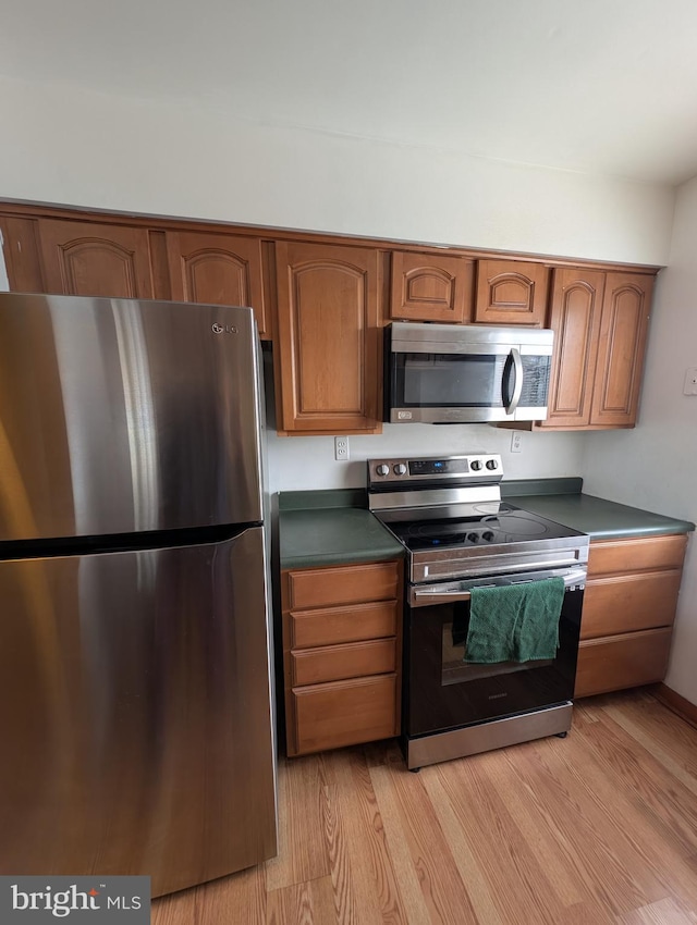 kitchen with light hardwood / wood-style floors and appliances with stainless steel finishes