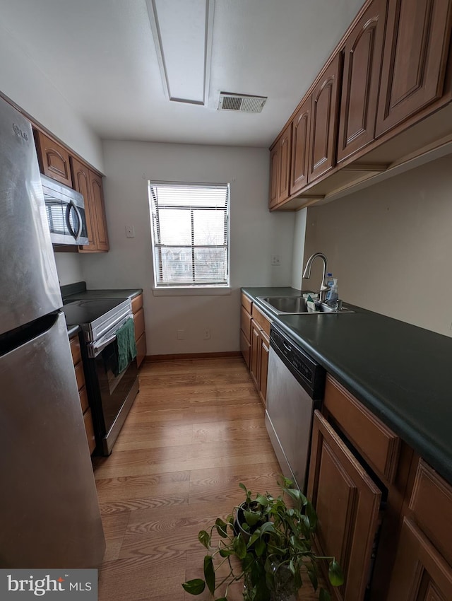 kitchen with sink, stainless steel appliances, and light hardwood / wood-style floors