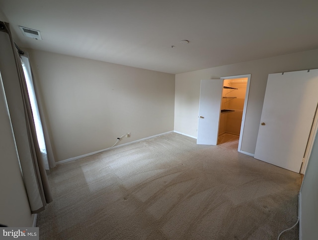 unfurnished bedroom with a spacious closet and light carpet