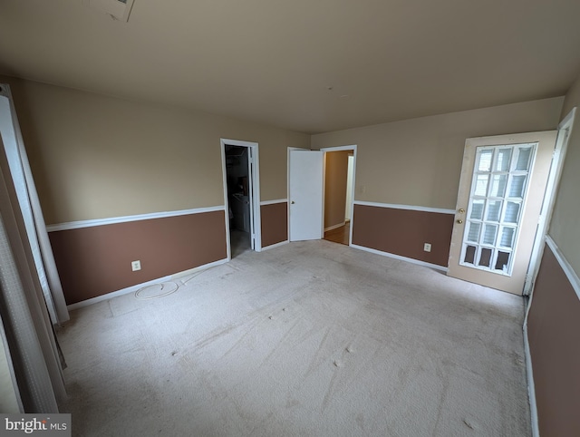 unfurnished bedroom with a spacious closet and light colored carpet