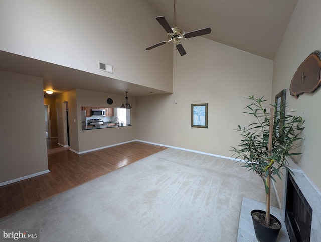 unfurnished living room featuring hardwood / wood-style flooring, high vaulted ceiling, and ceiling fan