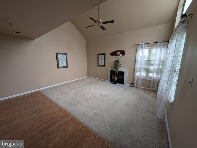 unfurnished living room with a premium fireplace, high vaulted ceiling, ceiling fan, and light wood-type flooring