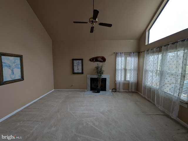 unfurnished living room featuring ceiling fan, a premium fireplace, high vaulted ceiling, and light carpet