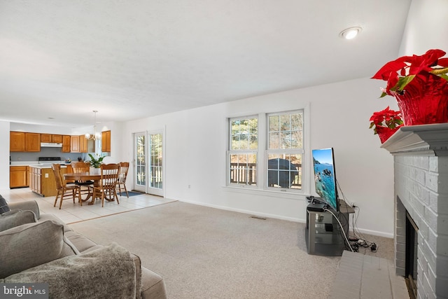 living room with a chandelier, light colored carpet, and a fireplace