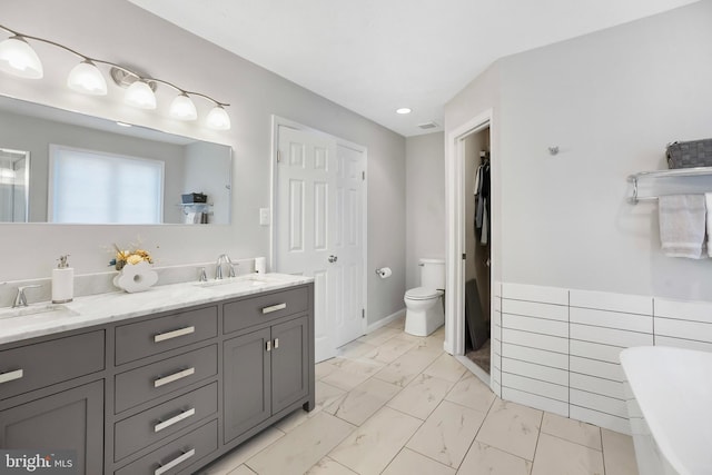 bathroom with vanity, a bathing tub, and toilet