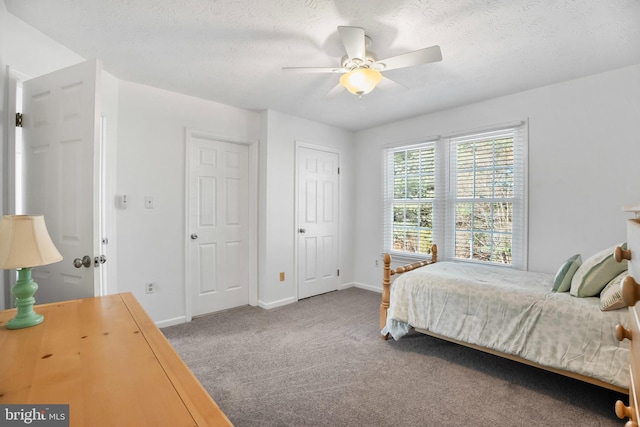 carpeted bedroom featuring ceiling fan and a textured ceiling