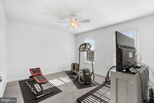 workout room with ceiling fan, dark carpet, and a textured ceiling