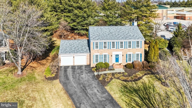 colonial house featuring a garage and a front lawn