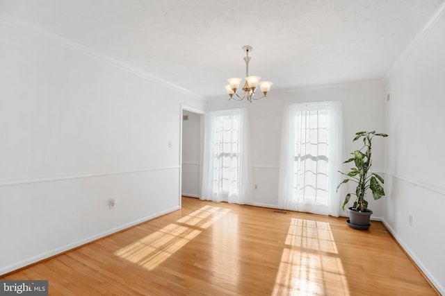 spare room with an inviting chandelier, crown molding, and light hardwood / wood-style floors