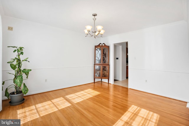 empty room featuring ornamental molding, hardwood / wood-style floors, and a chandelier