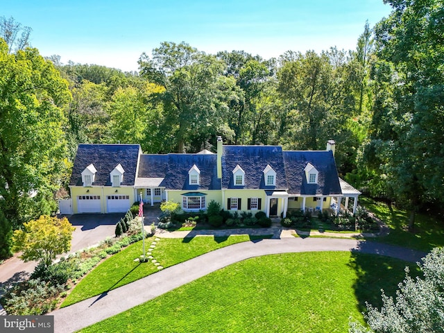 new england style home featuring a garage, driveway, and a front yard