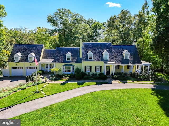 cape cod house featuring driveway, a front lawn, a chimney, and an attached garage